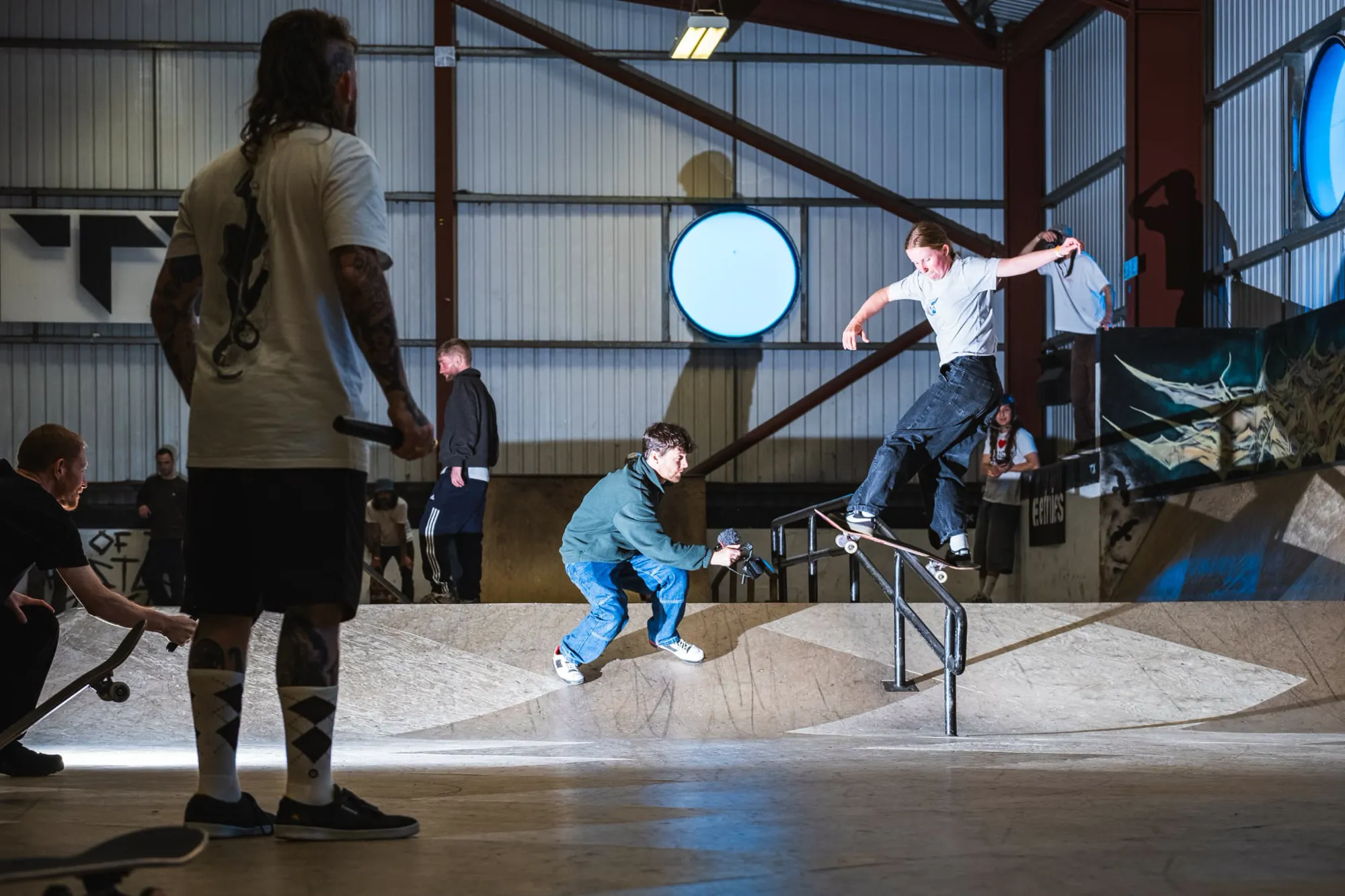 A skateboarder grinds a rail in the indoor park